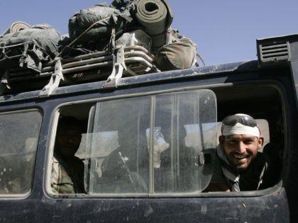 JALREZ, AFGHANISTAN - SEPTEMBER 04: A man smiles as he looks out a vehicle's window while Afghan troops travel near Jalrez, Afghanistan with U.S. advisors deploying from Kabul September 4, 2005 in Jalrez, Afghanistan. The convoy passed through Jalrez en route to outlying provinces to provide extra security for the …