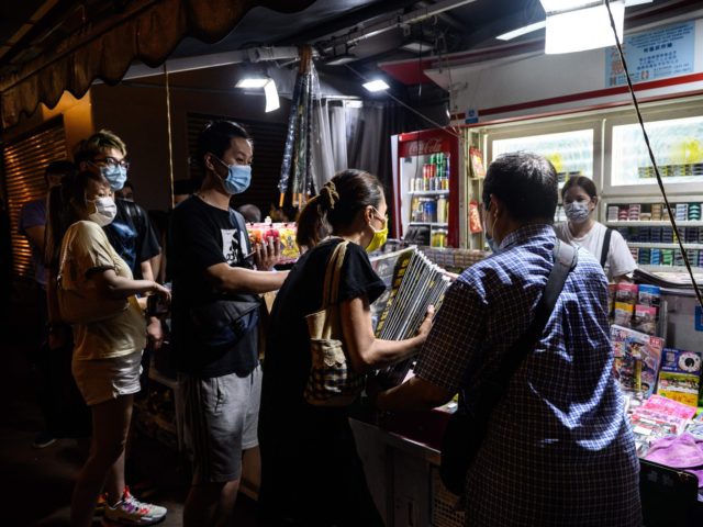 A customer (C) buys multiple copies of the Apple Daily newspaper after they were delivered from the media company's printing facility to a newsstand in Hong Kong early on June 18, 2021, after police arrested the chief editor and four executives of the pro-democracy newspaper the previous morning, raiding its …