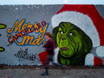 TOPSHOT - A mural painting by graffiti artist Eme Freethinker features a likeness of US author Dr Seuss' Grinch character with a "cancelled" stamp across a Merry Christmas sign, in Berlin on December 27, 2020. (Photo by John MACDOUGALL / AFP) / RESTRICTED TO EDITORIAL USE - MANDATORY MENTION OF …