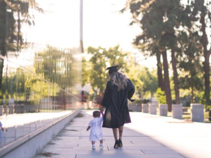 Graduate walking with a baby.