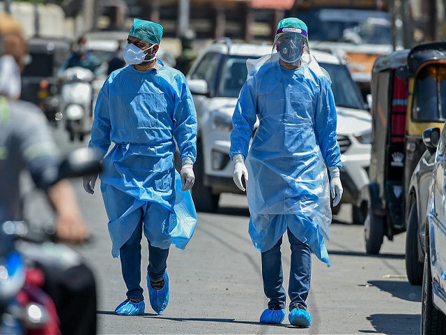 Doctors wearing protective gear walk among vehicles during a government-imposed nationwide