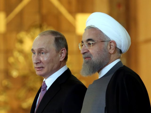 Iranian President Hassan Rouhani (R) talks with his Russian counterpart Vladimir Putin dur