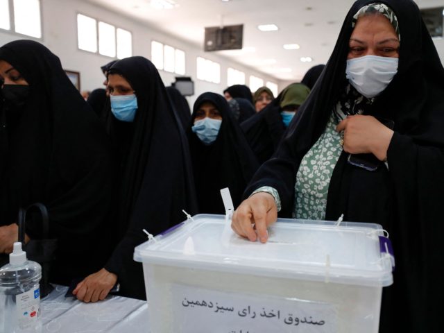 An Iranian woman casts her vote during the presidential election in their country, at a po