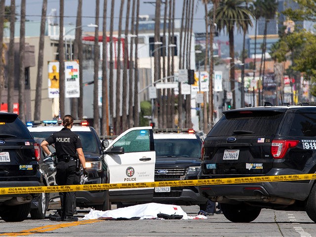 A LAPD police officer stands at the corner of Fairfax Avenue and Sunset Boulevard where a body covered in a white sheet lies on the pavement in Los Angeles on April 24, 2021 in what appears to be an officer-involved shooting. - On the evening of the shooting the LAPD …