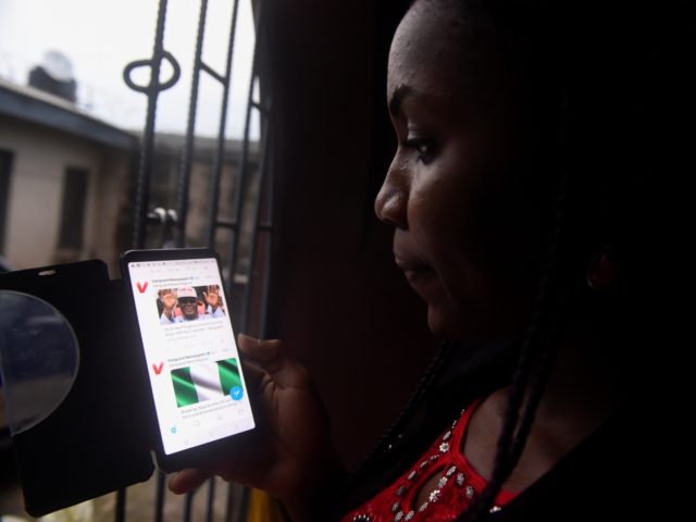 A lady tries to tweet with a smartphone in Lagos, on October 29, 2018. - Nigeria has an unenviable reputation around the world for corruption and is known particularly for its "419" email scams, named after the section of the penal code covering fraud. Fake social media accounts of celebrities, …