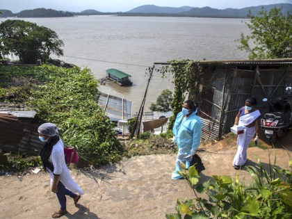 A heath worker in protection suit with others walk on a road to take nasal swab sample to