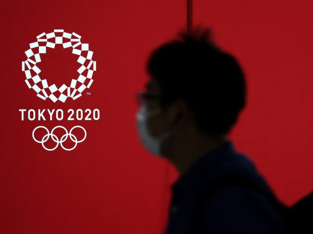A pedestrian walks past a Tokyo 2020 Olympic Games logo on a decoration board in Tokyo on April 7, 2021. (Photo by Yuki IWAMURA / AFP) (Photo by YUKI IWAMURA/AFP via Getty Images)