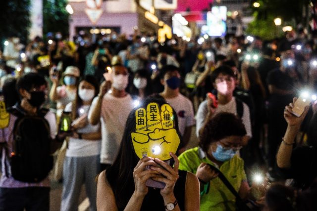 People hold up their phones with the light on in Hong Kong in remembrance of China's