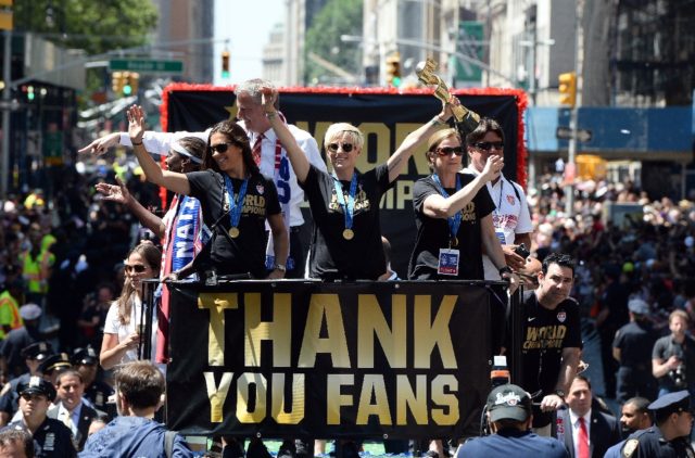 The US women's soccer team holds up the World Cup 2015 trophy during a parade in New York