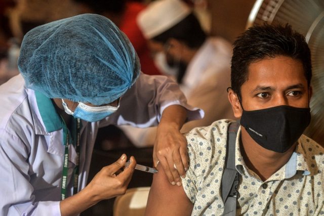 A health worker inoculates a man with a dose of the Oxford-AstraZeneca Covid-19 vaccine at