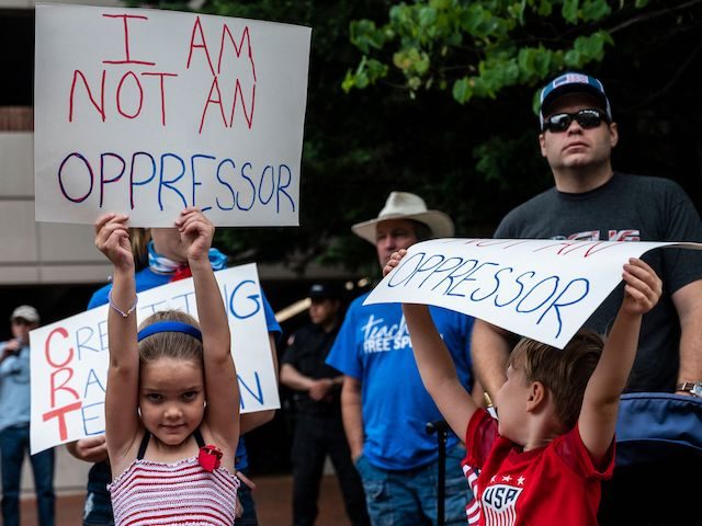 People hold up signs during a rally against "critical race theory" (CRT) being taught in s