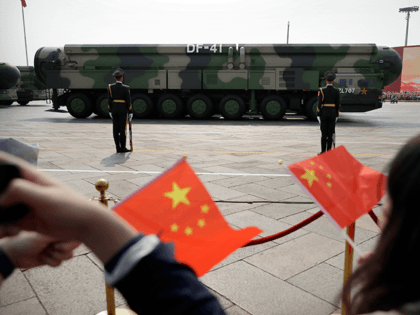 In this Oct. 1, 2019, file photo spectators wave Chinese flags as military vehicles carrying DF-41 ballistic missiles roll during a parade to commemorate the 70th anniversary of the founding of Communist China in Beijing. Trucks carrying weapons including a nuclear-armed missile designed to evade U.S. defenses rumbled through Beijing …