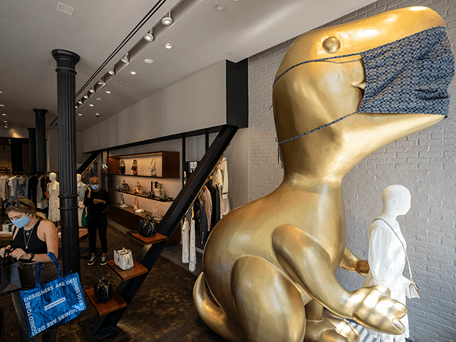 A mask is placed on a giant dinosaur statue as shoppers browse a Coach store in the retail shopping area of the SoHo neighborhood of the Manhattan borough of New York, Friday, May 14, 2021. Gov. Andrew Cuomo has yet to say whether he will change his stateâ€™s mask mandate …