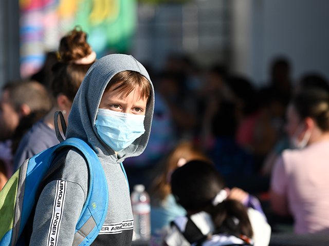 A masked student waits before the bell at Enrique S. Camarena Elementary School, Wednesday