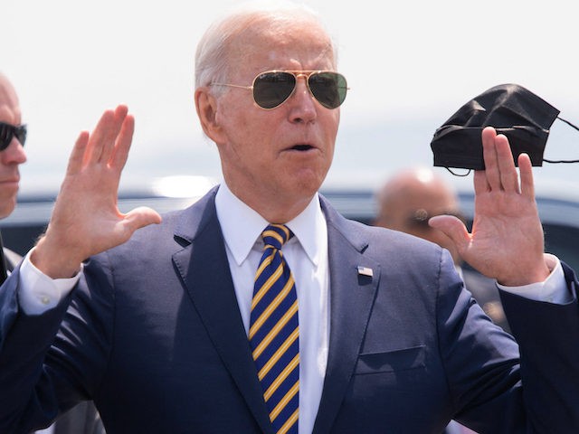 US President Joe Biden answers a question from the press as he holds a mask upon arrival o