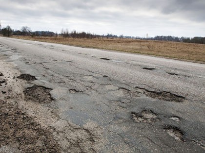 Badly damaged country asphalt road after winter