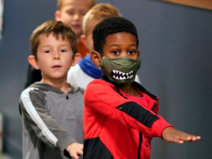 Students waking in the hallway at Tibbals Elementary School place their arms in front as a reminder to socially distance in Murphy, Texas, Thursday, Dec. 3, 2020. Texas Gov. Greg Abbot's statewide mask order does not mandate face covering for children under the age of 10, allowing some school districts …