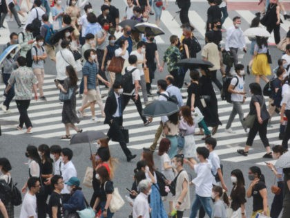 People wearing face masks to protect against the spread of the coronavirus cross a street in Tokyo, Wednesday, July 28, 2021. Tokyo Gov. Yuriko Koike on Wednesday urged younger people to cooperate with measures to bring down the high number of infections and get vaccinated, saying their activities are key …