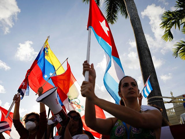 People hold Cuban, Peruvian and Venezuelan flags during a protest showing support for Cubans demonstrating against their government, at Versailles Restaurant in Miami, on July 18, 2021. - Cuba's President Miguel Diaz-Canel on July 17 denounced what he said was a false narrative over unrest on the Caribbean island, as …