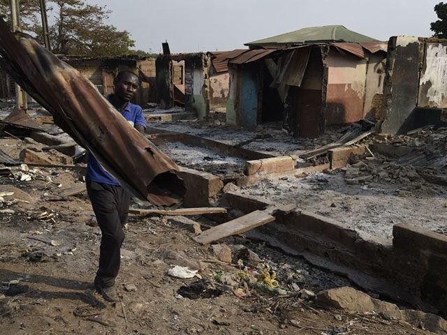 TOPSHOT - A man carries iron sheet salvaged from burnt shop after deadly ethnic clashes between the northern Fulani and southern Yoruba traders at Shasha Market in Ibadan, southwest Nigeria, on February 15, 2021. - Nigerian President vowed to protect all religious and ethnic groups in the country after deadly …