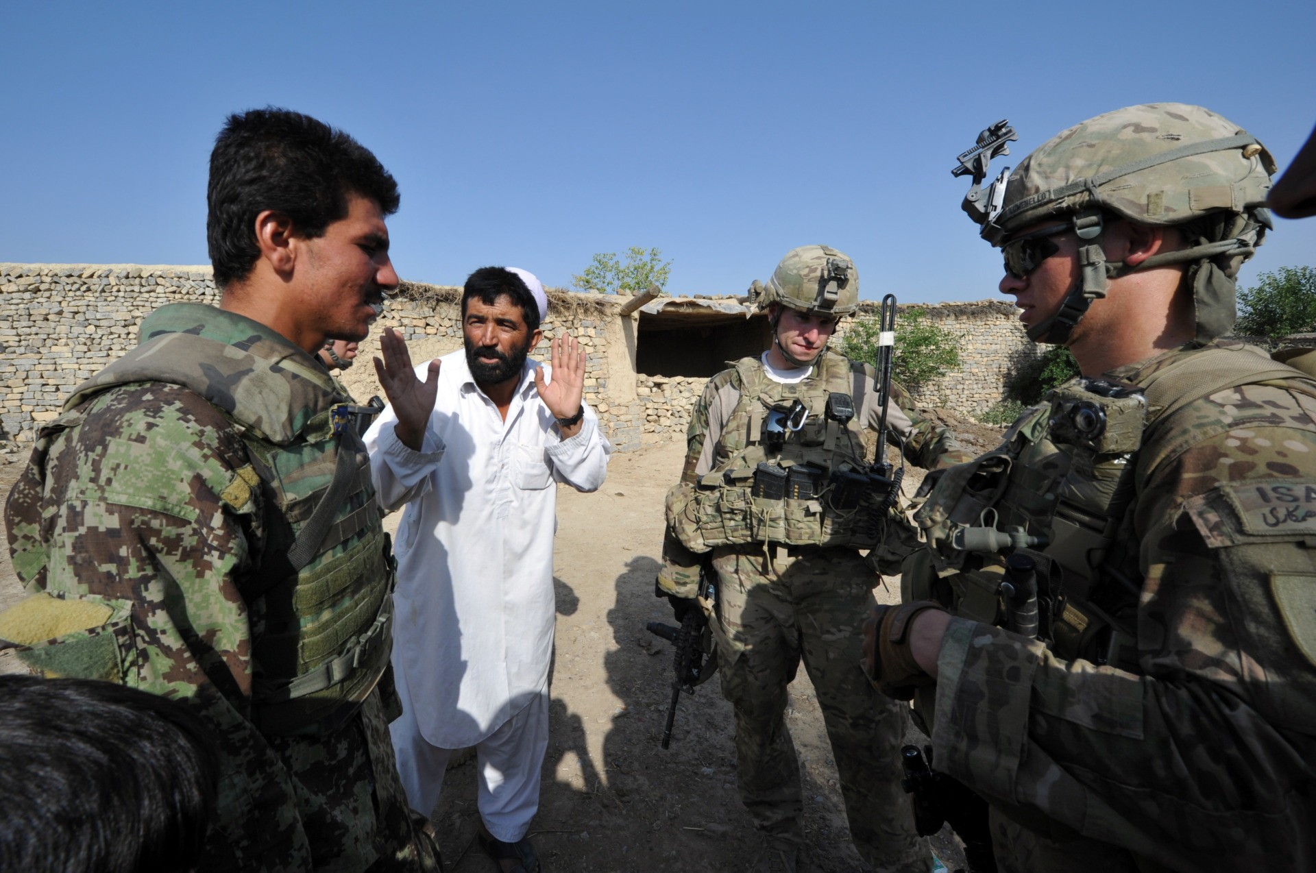 An Afghan soldier (L) serves an interpreter as a civilian talks to US soldiers from Viper Company (Bravo), 1-26 Infantry during a patrol at a village near Combat Outpost (COP) Sabari in Khost province in eastern Afghanistan June 19, 2011. Defense Secretary Robert Gates confirmed June 19, that US officials were involved in preliminary talks with the Taliban to seek a political solution to the Afghan war but said he didn't expect significant progress for months. AFP PHOTO/TED ALJIBE (Photo credit should read TED ALJIBE/AFP via Getty Images)