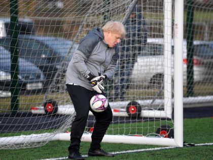 Britain's Prime Minister Boris Johnson tries to save a shot during a warm up before a girls football match while on the campaign trail in Cheadle Hulme, northwest England on December 7, 2019. - Britain will go to the polls on December 12, 2019 to vote in a pre-Christmas general …