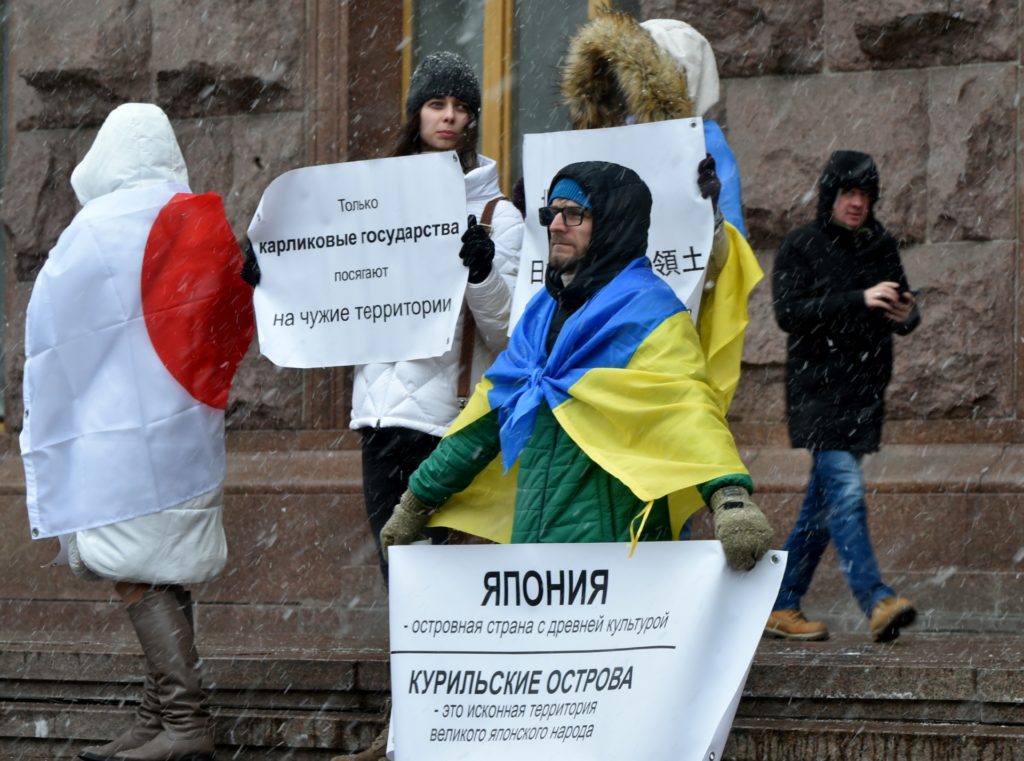 Activists covered with Ukrainian and Japanese flags hold placards reading "Kuril Islands are an original territory of the great Japanese people" and "Russia doesn't care about its own territory but likes the others" as they demonstrate in central Kiev to show solidarity with Japan marking Northern Territories Day on February 7, 2020. - Japan maintains its claim over the four southernmost islands of the Kuril chain, known as the Northern Territories in Japan. Nationalist sentiment on both sides - Russia and Japan - makes both governments wary of considering concessions. (Photo by Sergei SUPINSKY / AFP) (Photo by SERGEI SUPINSKY/AFP via Getty Images)