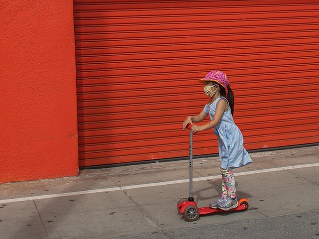 TOPSHOT - A girl wearing a mask, rides a scooter by the closed stores of the Boardwalk in Venice, California on April 26, 2020. - Los Angeles County beaches are still off limits under the countys "Safer at Home" order scheduled to be enforced through at least May 15 amid …