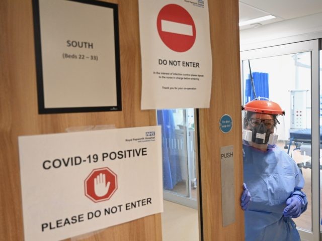 A member of the clinical staff wearing personal protective equipment (PPE) is seen at the entrance to a unit caring for patients that have tested positive for the COVID-19 illness at Royal Papworth Hospital in Cambridge, on May 5, 2020. - NHS staff wear an enhanced level of PPE in …