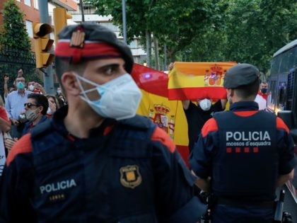 Demonstrators hold up Spanish flags in front of police, during a protest on May 20, 2020,