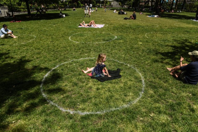 NEW YORK, NY - MAY 22 : A young girl sits inside a painted circle for social distancing o