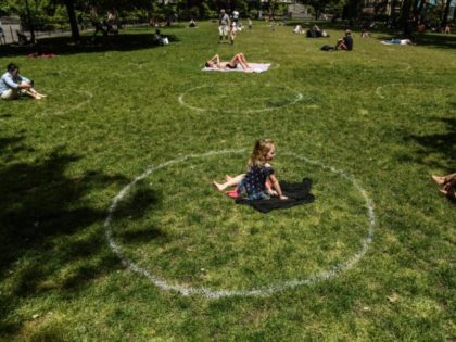NEW YORK, NY - MAY 22 : A young girl sits inside a painted circle for social distancing on May 22, 2020 In Madison Square Park in New York City. New York City is currently in its ninth week of lockdown and governmental guidelines on wearing a mask in public …