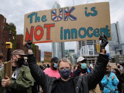 Protesters, some wearing PPE (personal protective equipment), including a face mask as a precautionary measure against COVID-19, hold placards during a protest march to the US Embassy in London on June 7, 2020, organised to show solidarity with the Black Lives Matter movement in the wake of the killing of …