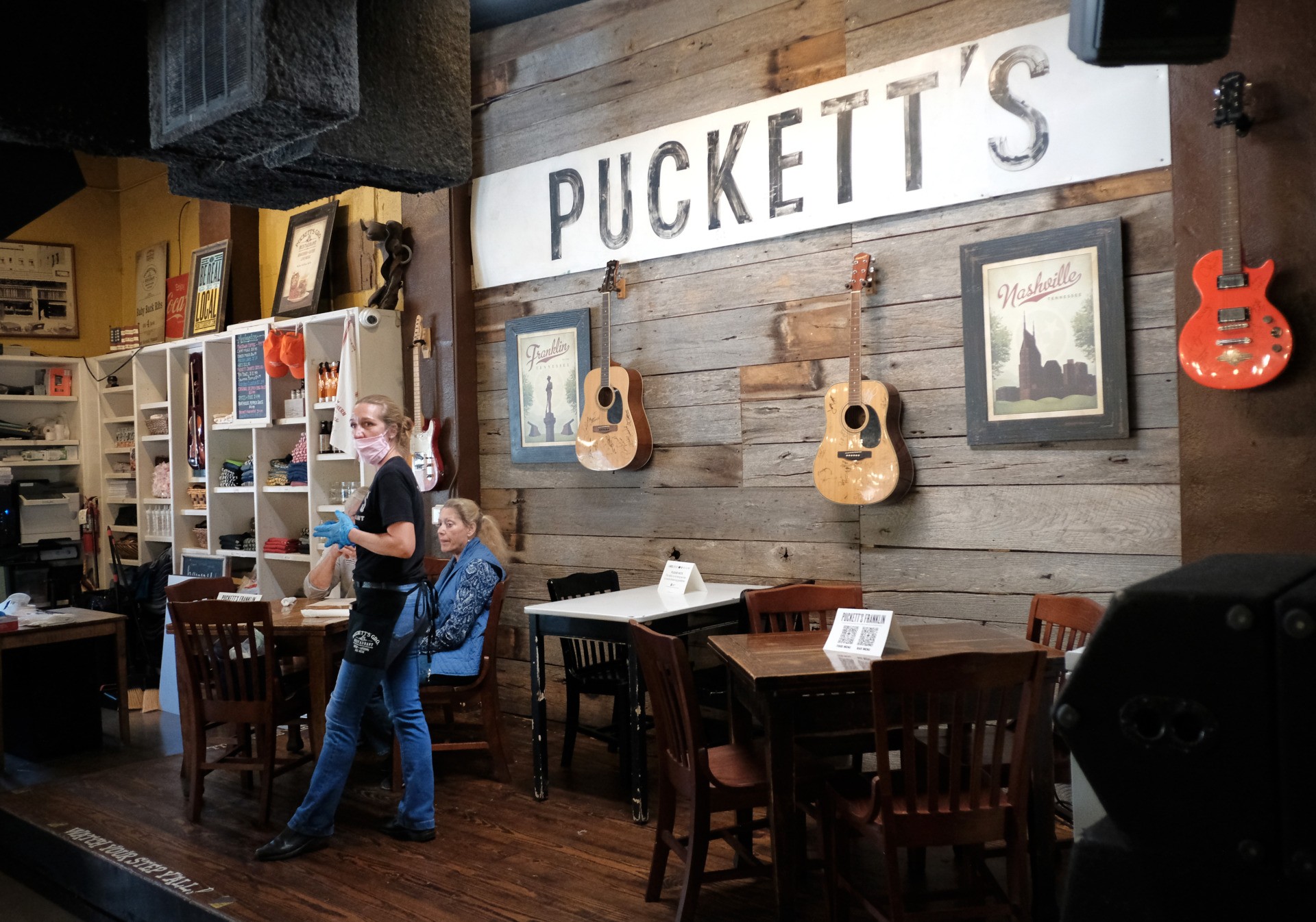 NASHVILLE, TENNESSEE - APRIL 27: A waitress wearing rubber gloves and a mask takes orders from patrons at Puckett's Grocery & Restaurant on April 27, 2020 in Franklin, Tennessee. Tennessee is one of the first states to reopen restaurants after the onset of the COVID-19 pandemic. Restaurants are permitted to open at 50 percent capacity but required to maintain social distancing. (Photo by Jason Kempin/Getty Images)