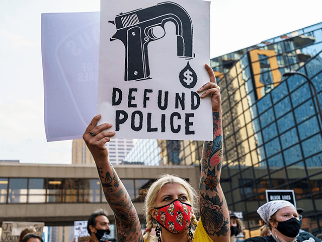 A Protester hold a sign reading "Defund the Police" outside Hennepin County Government Pla
