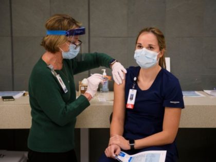 Traveling registered nurse Taylor Reed (R) receives a Covid-19 vaccination at Martin Luther King Jr. (MLK) Community Hospital on January 6, 2021 in the Willowbrook neighborhood of Los Angeles, California. - Deep within a South Los Angeles hospital, a row of elderly Hispanic men in induced comas lay hooked up …
