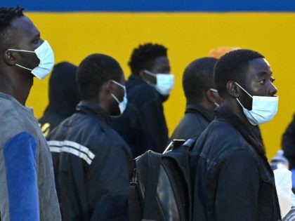 Migrants from a migrant housing centre on the Italian island of Lampedusa, are watched by