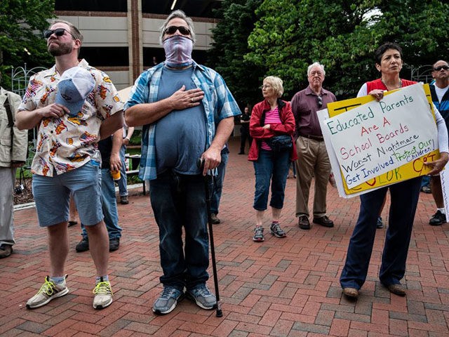 People hold up signs during a rally against "critical race theory" (CRT) being taught in schools at the Loudoun County Government center in Leesburg, Virginia on June 12, 2021. - "Are you ready to take back our schools?" Republican activist Patti Menders shouted at a rally opposing anti-racism teaching that …