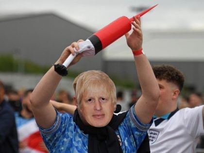 An England supporter wearing a Prime Minister Boris Johnson mask poses for a photograph before cheering on his team at the 4TheFans Fan Park in Manchester while watching the UEFA EURO 2020 football match between England and Scotland being played in London on June 18, 2021. (Photo by Oli SCARFF …