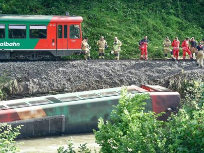 Emergency personnel work close to a railway car that has fallen into the river Mur at the