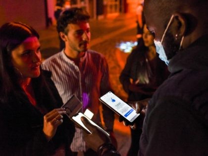 Security staff member checks the health pass of a client, at the entrance of a nightclub in Saint-Jean-de-Monts, western France, on early July 10, 2021. - Nightlife fans across France can once again crowd into clubs starting July 9, 2021, though officials warned they would remain vigilant against any surge …