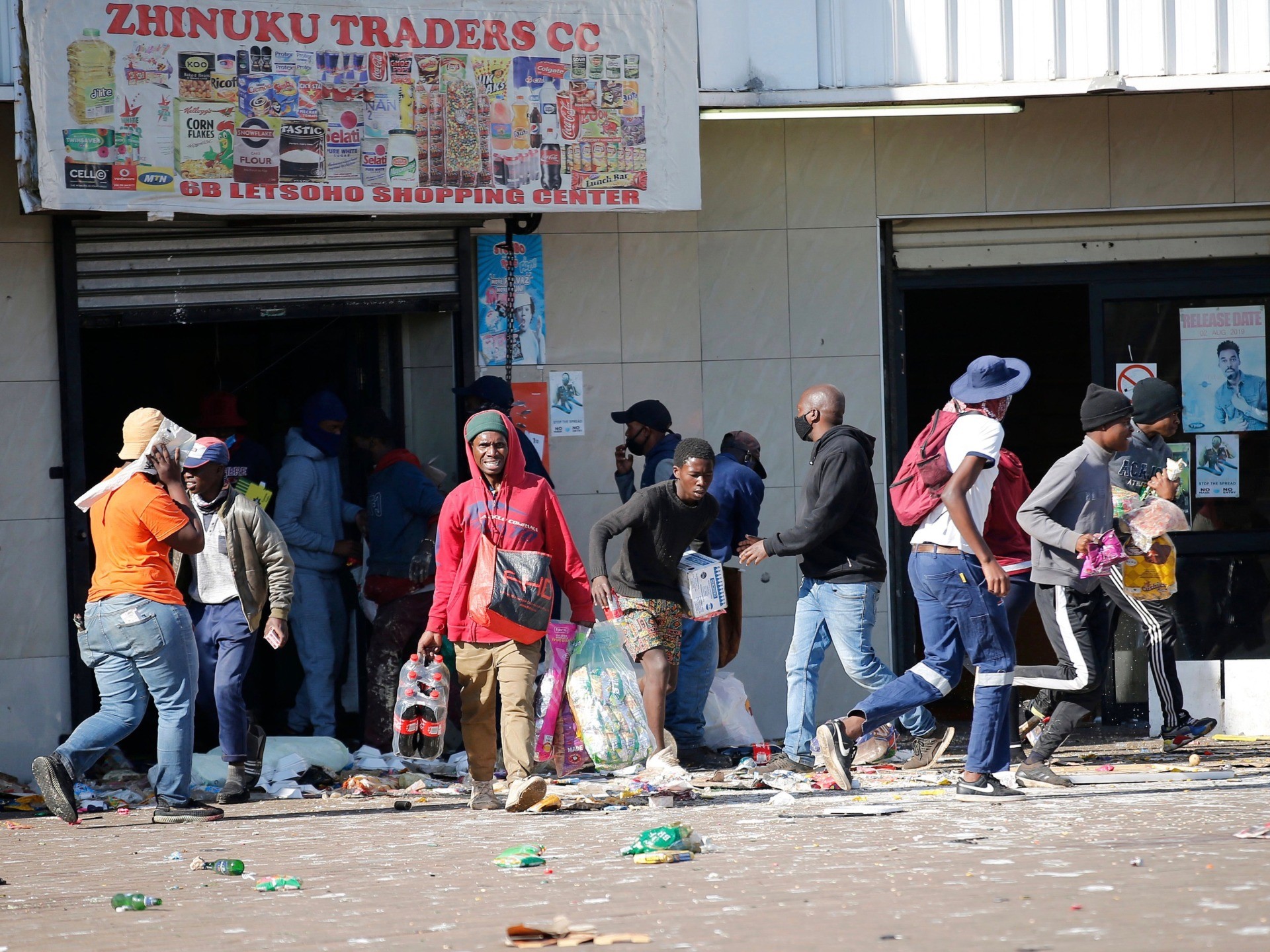 People carry goods as they loot and vandalise the Lotsoho Mall in Katlehong township, East of Johannesburg, on July 12, 2021. Several shops are damaged and cars burnt in Johannesburg, following a night of violence. Police are on the scene trying to control further protests. It is unclear if this is linked to sporadic protests following the incarceration of former president Jacob Zuma. (Photo by Phill Magakoe / AFP) (Photo by PHILL MAGAKOE/AFP via Getty Images)