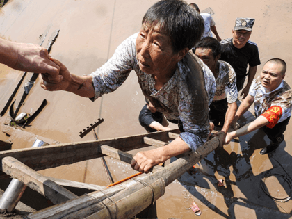 This photo taken on July 12, 2021 shows village officials evacuating residents from a flooded area following heavy rains in Dazhou in China's southwestern Sichuan province. - China OUT (Photo by STR / AFP) / China OUT (Photo by STR/AFP via Getty Images)