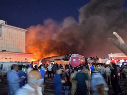 People gather as a massive fire engulfs the coronavirus isolation ward of Al-Hussein hospital in the southern Iraqi city of Nasiriyah, late on July 12, 2021. (Photo by Asaad NIAZI / AFP) (Photo by ASAAD NIAZI/AFP via Getty Images)