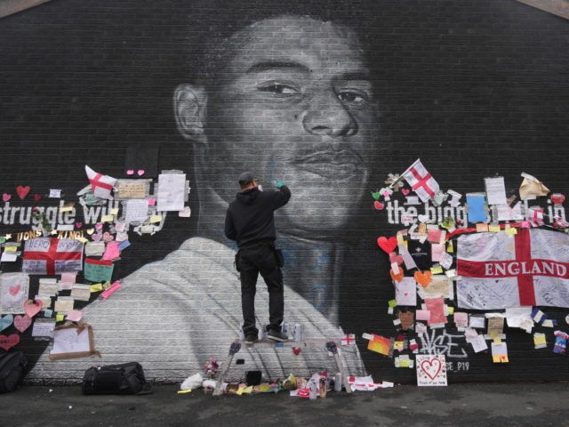 MANCHESTER, ENGLAND - JULY 13: The artist known as AKSE_P19, who painted the mural of England footballer Marcus Rashford which is displayed on the wall of a cafe on Copson Street, Withington, sets about repairing it after it was defaced by vandals in the aftermath of England's Euros loss on …