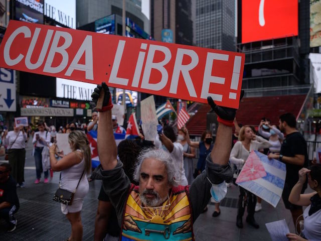 TOPSHOT - Demonstrators hold placards during a rally held in solidarity with anti-government protests in Cuba, in Times Square, New York on July 13, 2021. - One person died and more than 100 others, including independent journalists and dissidents, have been arrested after unprecedented anti-government protests in Cuba, with some remaining in custody on Tuesday, observers and activists said. (Photo by Ed JONES / AFP) (Photo by ED JONES/AFP via Getty Images)