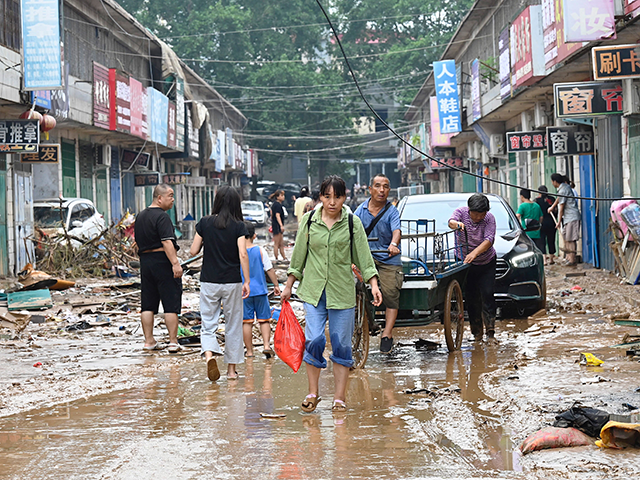 A woman carries a bag on a muddy street after severe flooding and landslide in recent days have hit the county-level Gongyi city, near Zhengzhou, in central Chinas Henan province on July 22, 2021. (Photo by JADE GAO / AFP) (Photo by JADE GAO/AFP via Getty Images)
