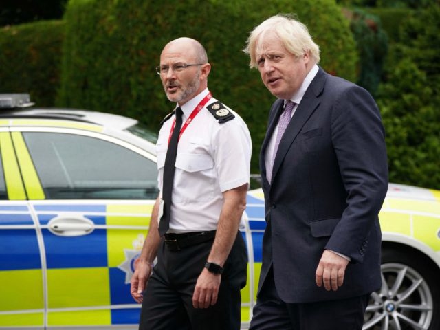 Britain's Prime Minister Boris Johnson (R) walks with Chief Constable Gavin Stephens (L) d