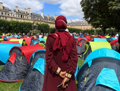 A woman watches as protestors set up tents during a demonstration called by the Utopia association to ask for housing for migrants and homeless people, on the Place des Vosges in Paris, on July 29, 2021. (Photo by Alain JOCARD / AFP) (Photo by ALAIN JOCARD/AFP via Getty Images)