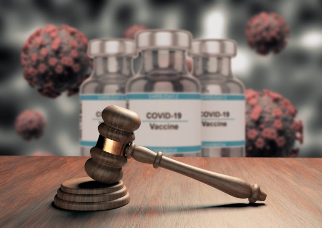 Judge gavel or law gavel on wooden table with coronavirus vaccine in the background. Conce